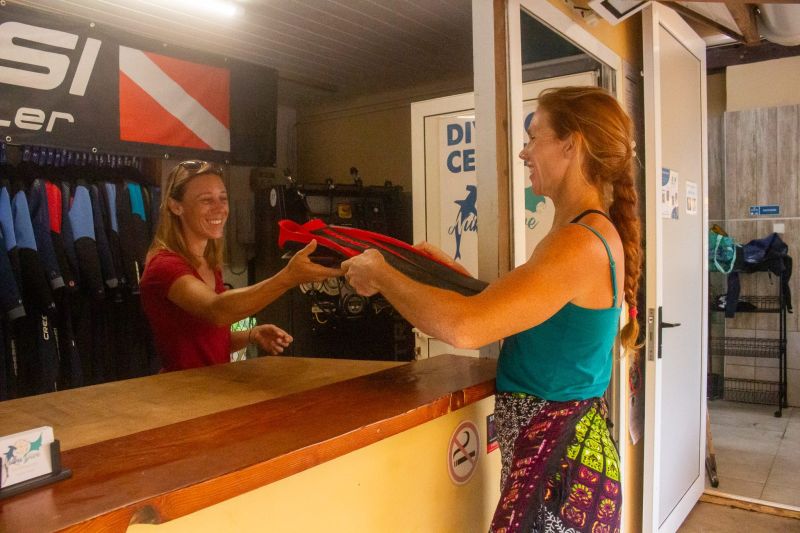 Handing fins to a guest at the dive centre desk