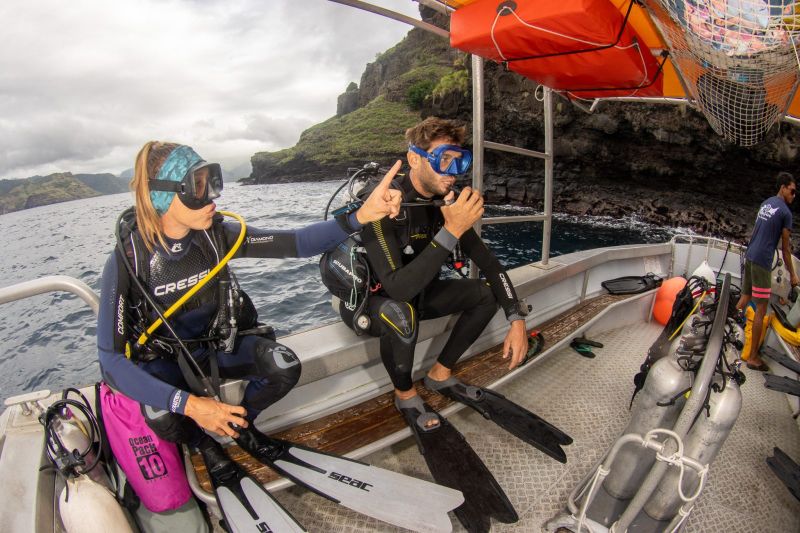 Divers sitting on the edge of the boat before the backward roll